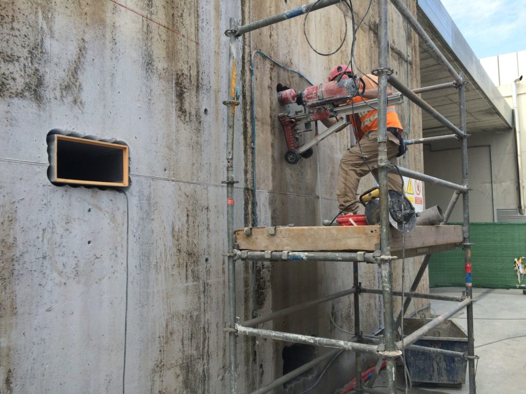 Peón de obra perforando un muro de cemento